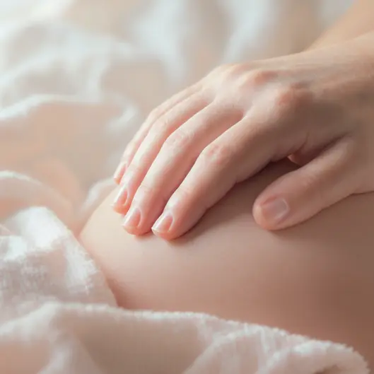 Bé mỉm cười thư thái khi được massage bụng, giúp cải thiện tiêu hóa và tăng cường miễn dịch.